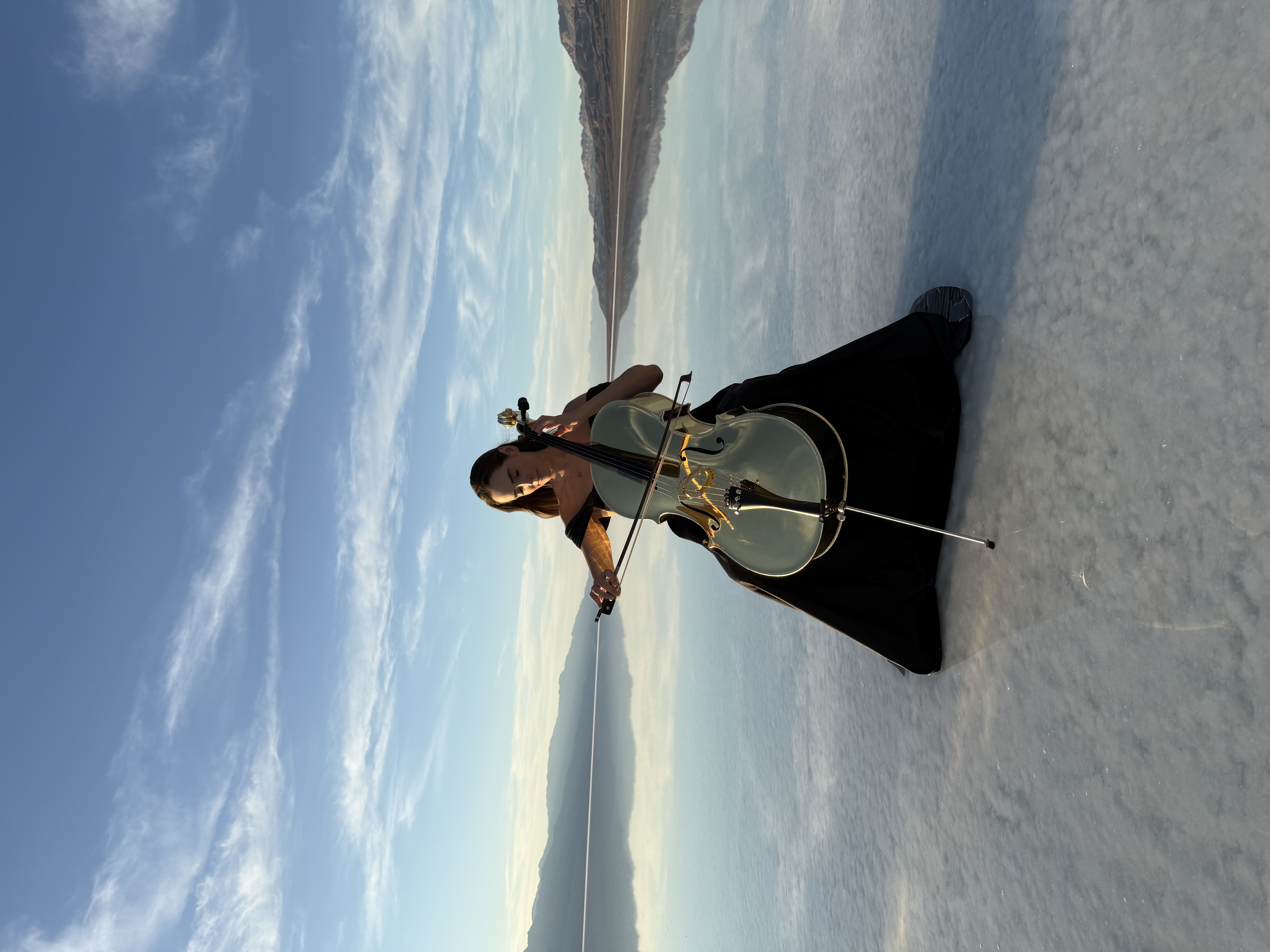 Golden Cello Girl performing on salt flat with golden cello and mirror reflections
